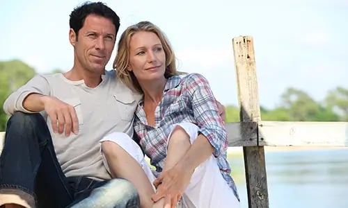 middle-aged-couple-sitting-oh-a-dock